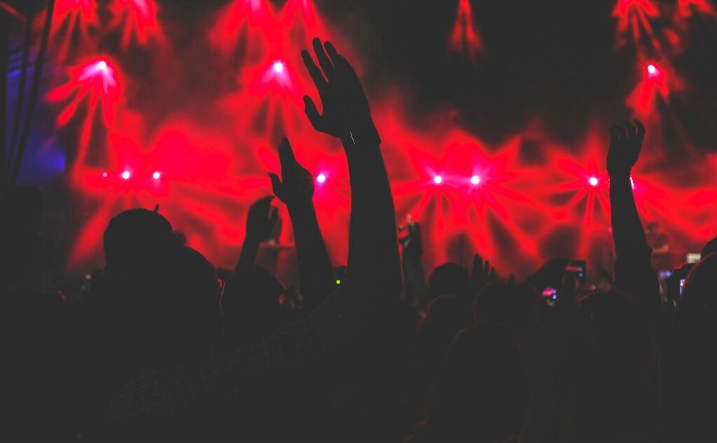 Público con las manos arriba bajo luces rojas